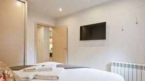 Une chambre d’hôtel équipée d’un lit, d’un téléviseur à écran plat fixé au mur, d’un radiateur et d’une porte donnant accès à une salle de bain.
