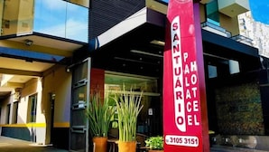 The exterior of a hotel named 'SANTAPOLATEL' with a modern architectural design, featuring balconies and a clear sky.