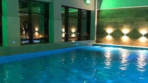 A swimming pool with clear blue water, surrounded by a modern building with glass doors and walls.