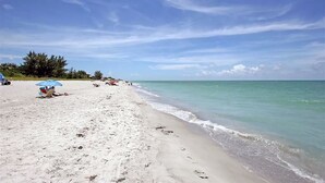 A beach with white sand, clear turquoise water, and a few umbrellas. - Sunset Captiva 17 (Captiva)