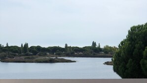 Un balcón con vista a un lago, una tumbona y un sombrero de paja.