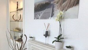 Una sala de estar con chimenea, una estantería y un cuadro de una playa.