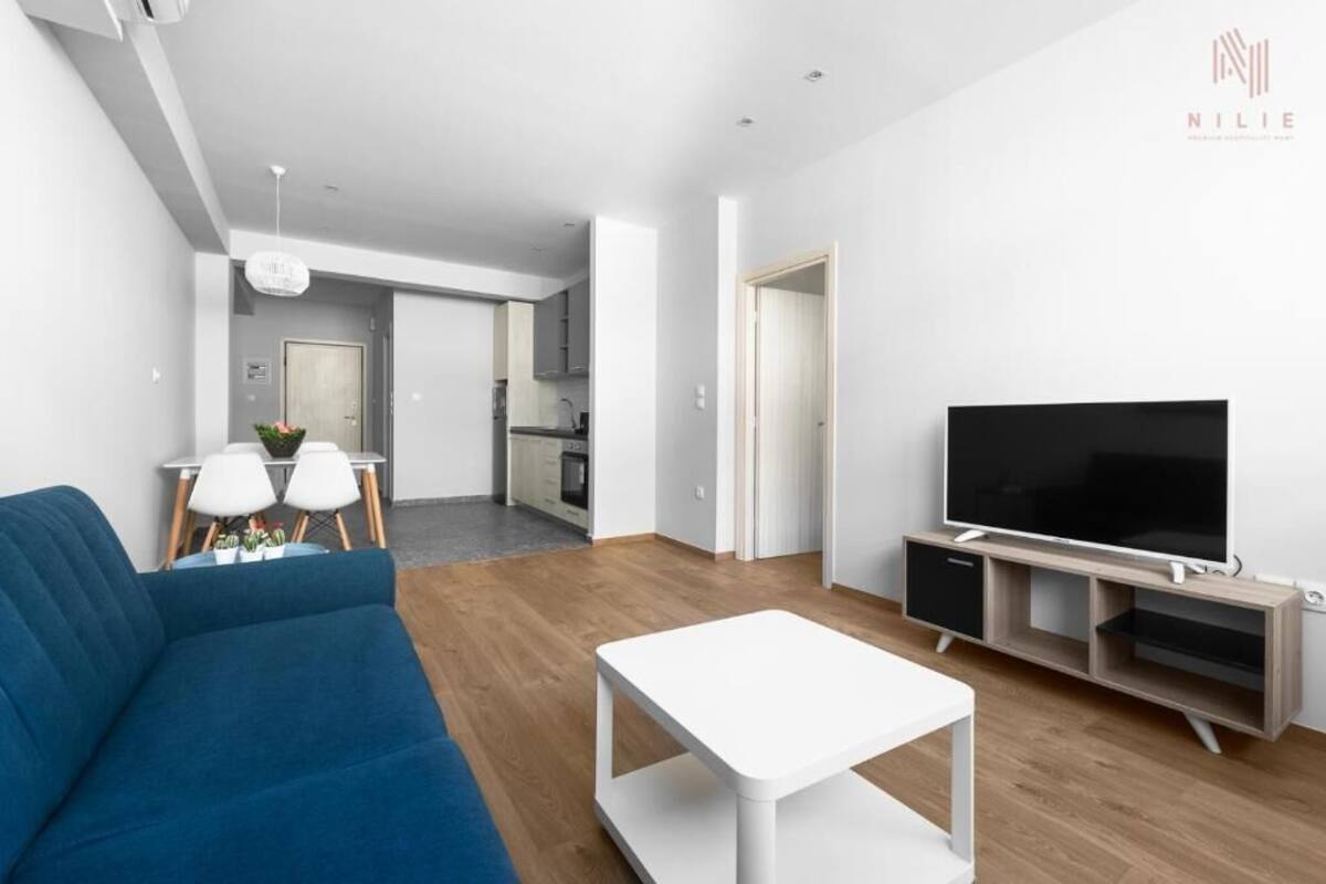 A modern living room with a blue sofa, a white coffee table, and a TV on a wooden stand.