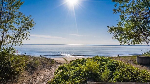 A beach view with a clear sky and sunlight reflecting on the water.