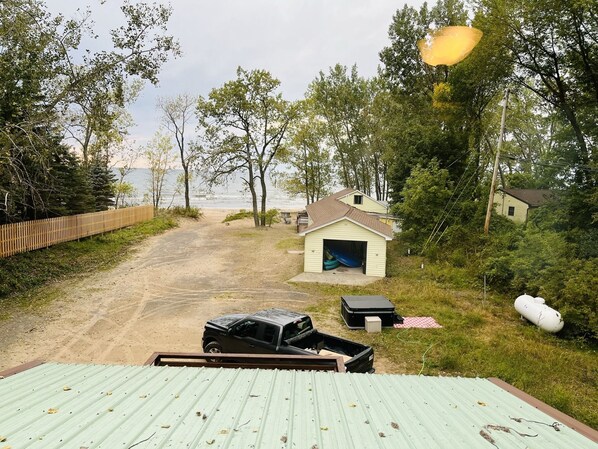A beach house with a garage, a covered deck, and a dirt path leading to the beach. - Lake Ontario Beach House Getaway-House #2 (Henderson)