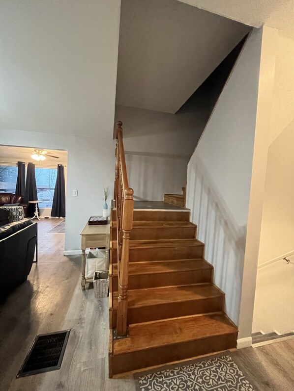 Una escalera de madera con escalones y barandilla que sube a un piso superior.