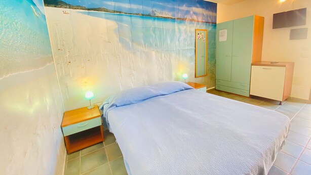 Un dormitorio con una cama, una mesita de noche, un aparador y un mural de playa en la pared.