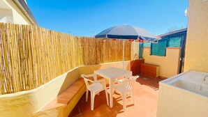 Un patio con una mesa y sillas, una pequeña zona de estar y una valla de madera.