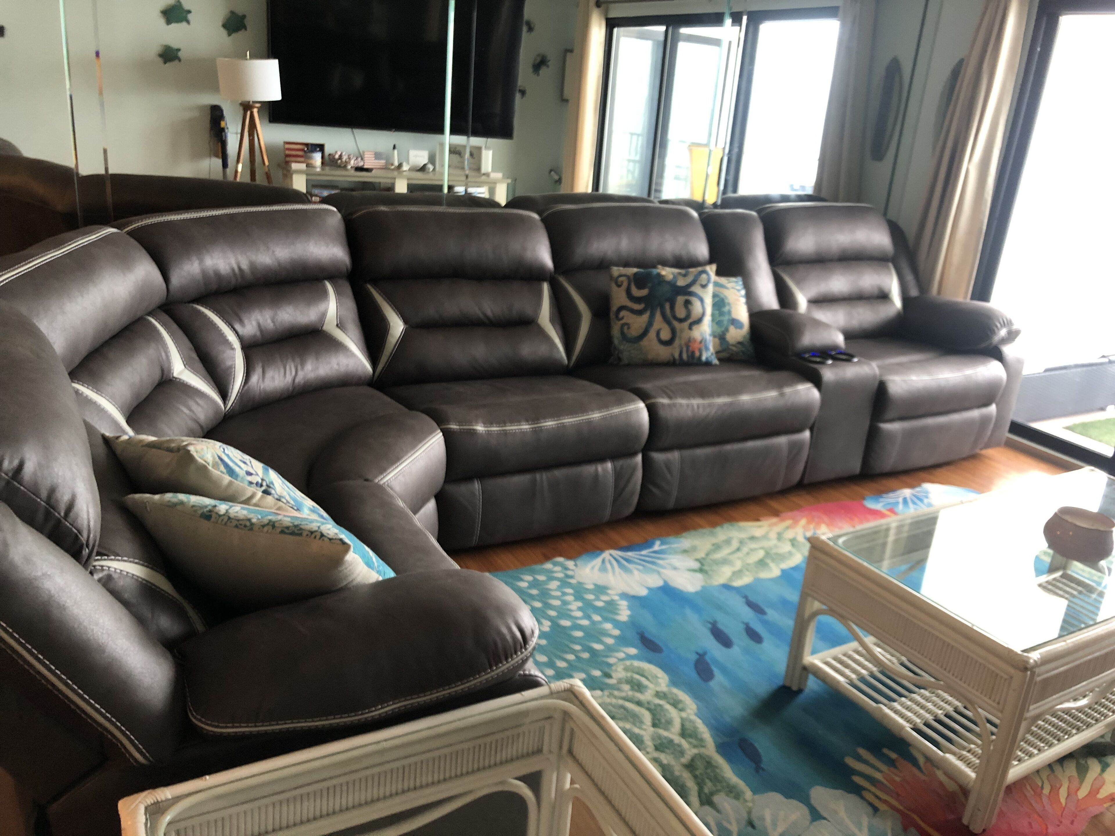 A sectional sofa with multiple cushions, a small white side table, and a colorful rug.