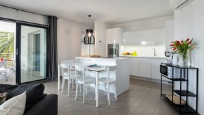 Eine moderne Küche mit weißen Schränken, einer zentralen Kochinsel mit Sitzgelegenheiten und einem Essbereich mit weißen Stühlen.