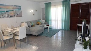 A modern living room with a dining area, a sofa, a coffee table, and a TV stand.