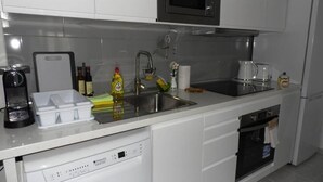 A modern kitchen with white cabinets, stainless steel appliances, a dishwasher, and a coffee maker.