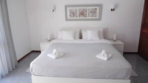 A neatly arranged bedroom with a large bed, two bedside tables, and a framed artwork above the bed.