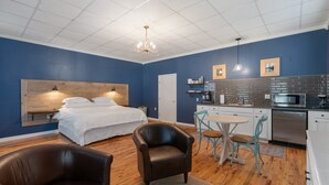 Een moderne kamer met een bed, bureau en kitchenette.