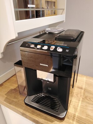 En Siemens-espressomaskin med ett digitalt användargränssnitt, en genomskinlig vattentank och en droppuppsamlare i rostfritt stål.