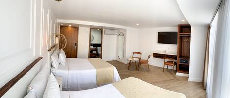 Habitación de hotel con dos camas, un escritorio, una silla, un televisor y un armario.