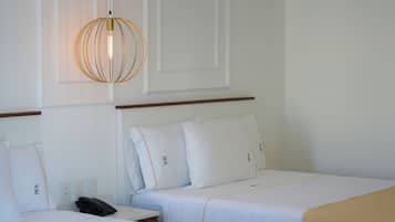 Une chambre d’hôtel avec deux lits simples, une table de chevet avec un téléphone et un luminaire suspendu.