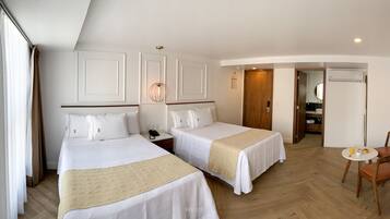 A hotel room with two beds, a dining area, and a TV.