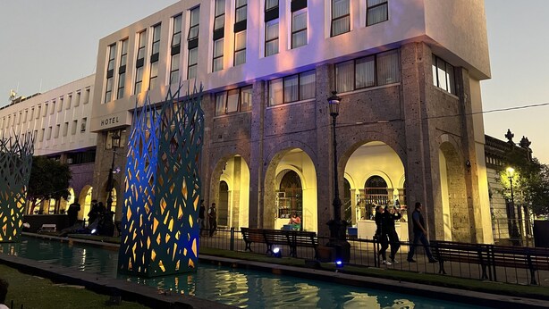 Un hotel con varios pisos, piscina e iluminación azul decorativa.