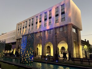Un hôtel à étages, doté d’une piscine et agrémenté d’une structure décorative illuminée de lumière bleue.
