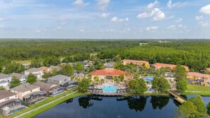 A residential area with a large house featuring a swimming pool, surrounded by smaller houses and a body of water. - 463 -4 bedroom villa with south facing private pool & Spa (Kissimmee)