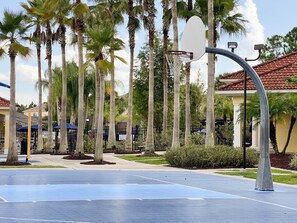 A basketball court with a hoop, surrounded by palm trees and a building with a red-tiled roof. - 463 -4 bedroom villa with south facing private pool & Spa (Kissimmee)
