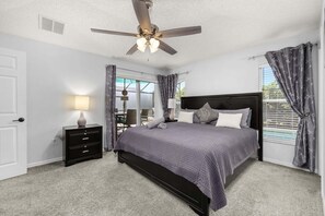 A bedroom with a bed, a nightstand, a ceiling fan, and a view through a window. - 463 -4 bedroom villa with south facing private pool & Spa (Kissimmee)