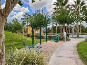 An outdoor exercise area with a pull-up bar, a bench, and a walking path.