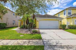 A residential driveway leading to a garage, surrounded by well-maintained lawns and mature trees. - 463 -4 bedroom villa with south facing private pool & Spa (Kissimmee)