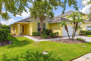 A residential house with a yellow exterior, a front lawn, and a driveway leading to a garage. - 463 -4 bedroom villa with south facing private pool & Spa (Kissimmee)