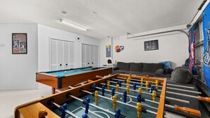 Ein Raum mit Tischfußball, Billardtisch und einer Couch.