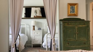 A bedroom with two beds, a nightstand with a lamp, a green dresser, and a mirror on the wall. - Tempurpedic beds, walk to food, play ping pong & fenced artificial turf yard (Austin)