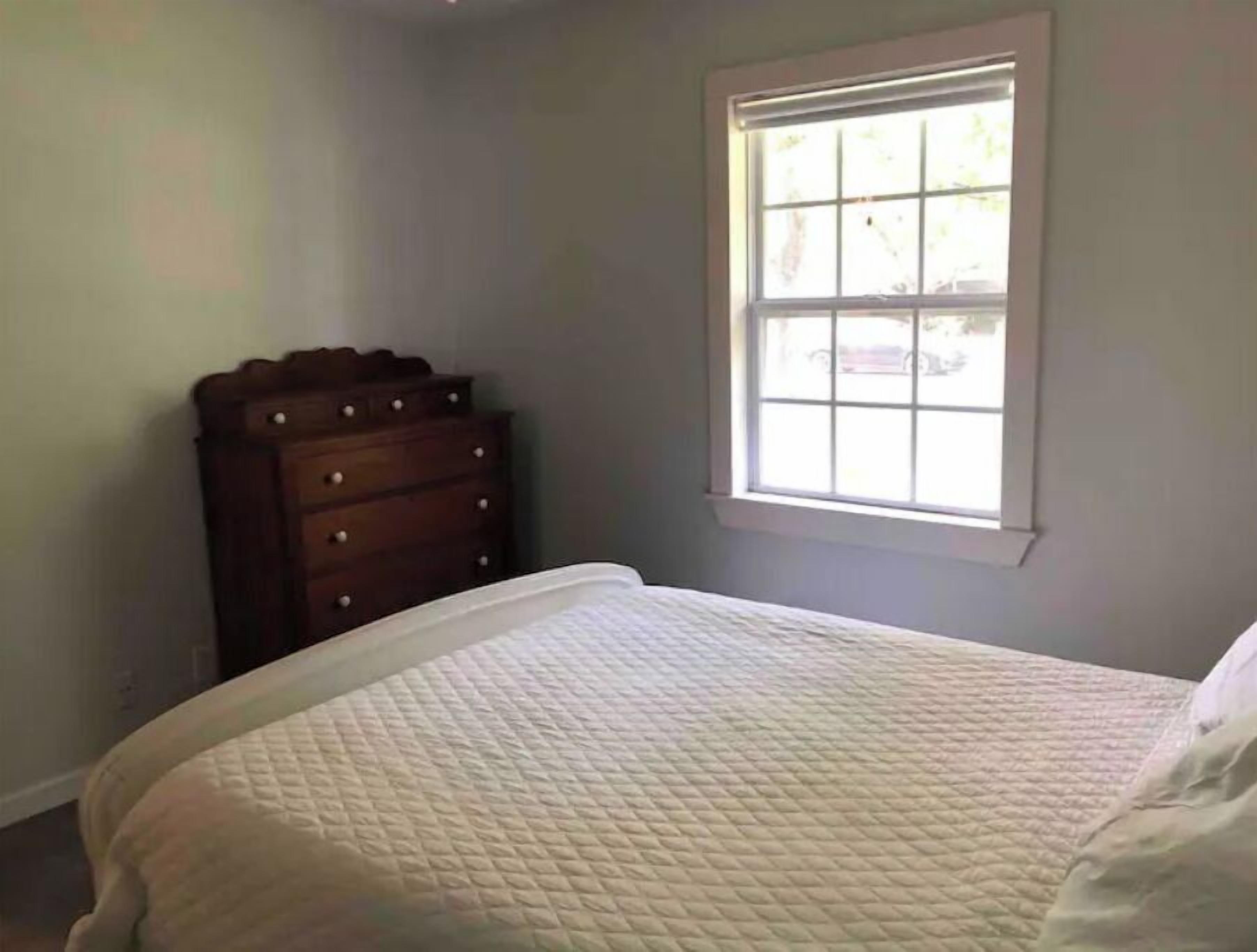 A bedroom with a bed, a dresser, and a window.