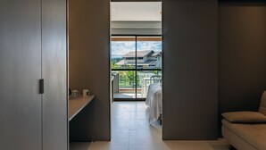 A modern room with a sliding door leading to a balcony with a view of buildings and greenery. - Apto Completo no Eco Resort (Rio Formoso)