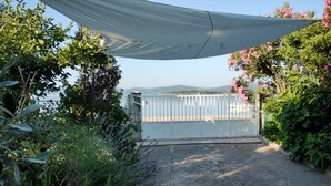 A paved pathway leading to a gated area with a view of a body of water and hills in the distance.