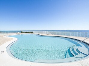 A clear blue swimming pool with a curved edge, a white deck surrounding it, and a white railing along the edge. - PENSACOLA / PERDIDO FALL DISCOUNTS  WATER FRONT RESORT DELUXE 3BED 3BA END SUITE (Pensacola)