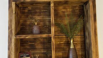 A wooden shelf with a book titled 'Sexton Blake Wins', a small vase with a plant, and a decorative item.