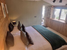 Un dormitorio con cama, almohadas, lámpara y ventana con vistas.