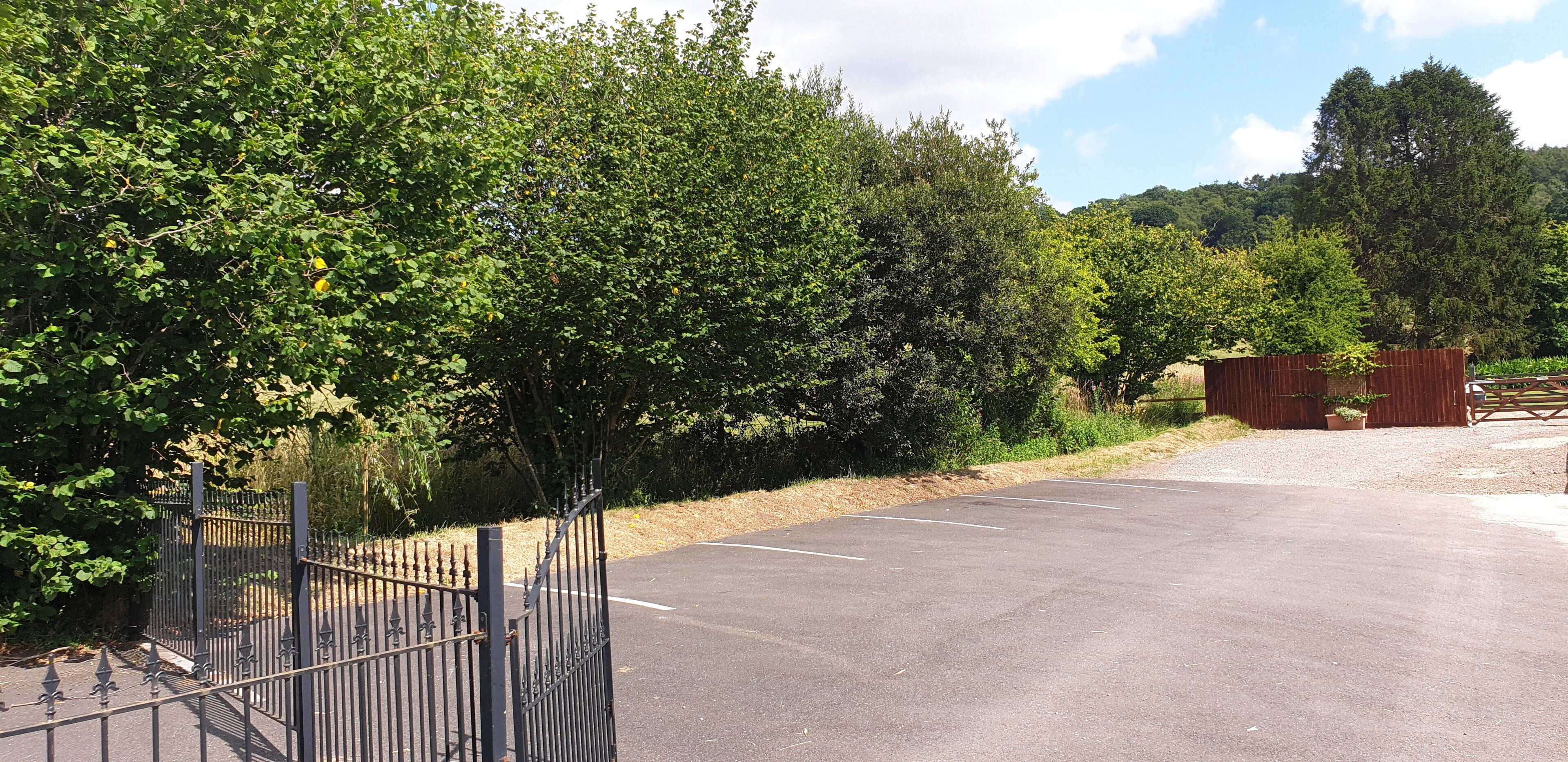 Un parking entouré d’une clôture métallique, avec des arbres en arrière-plan.