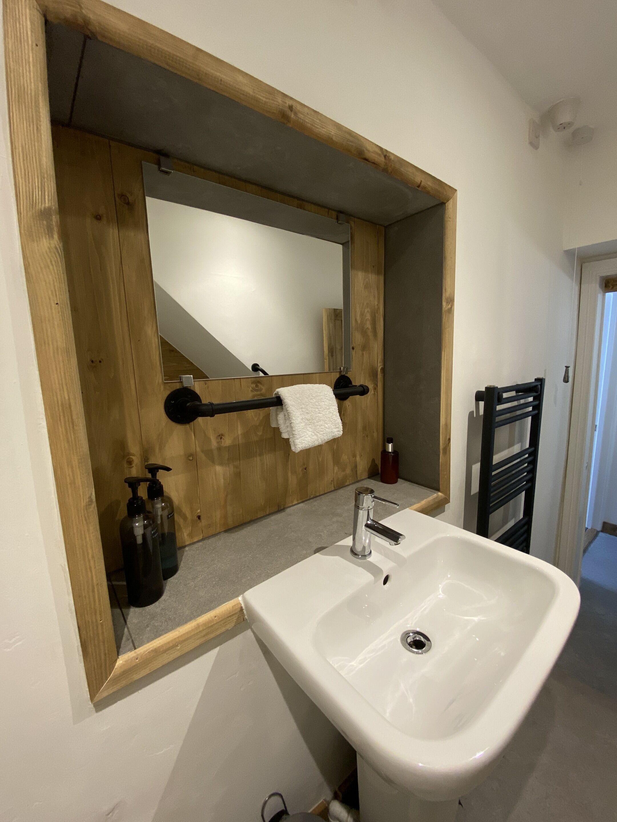 A bathroom with a wooden vanity, a white sink, and a mirror.