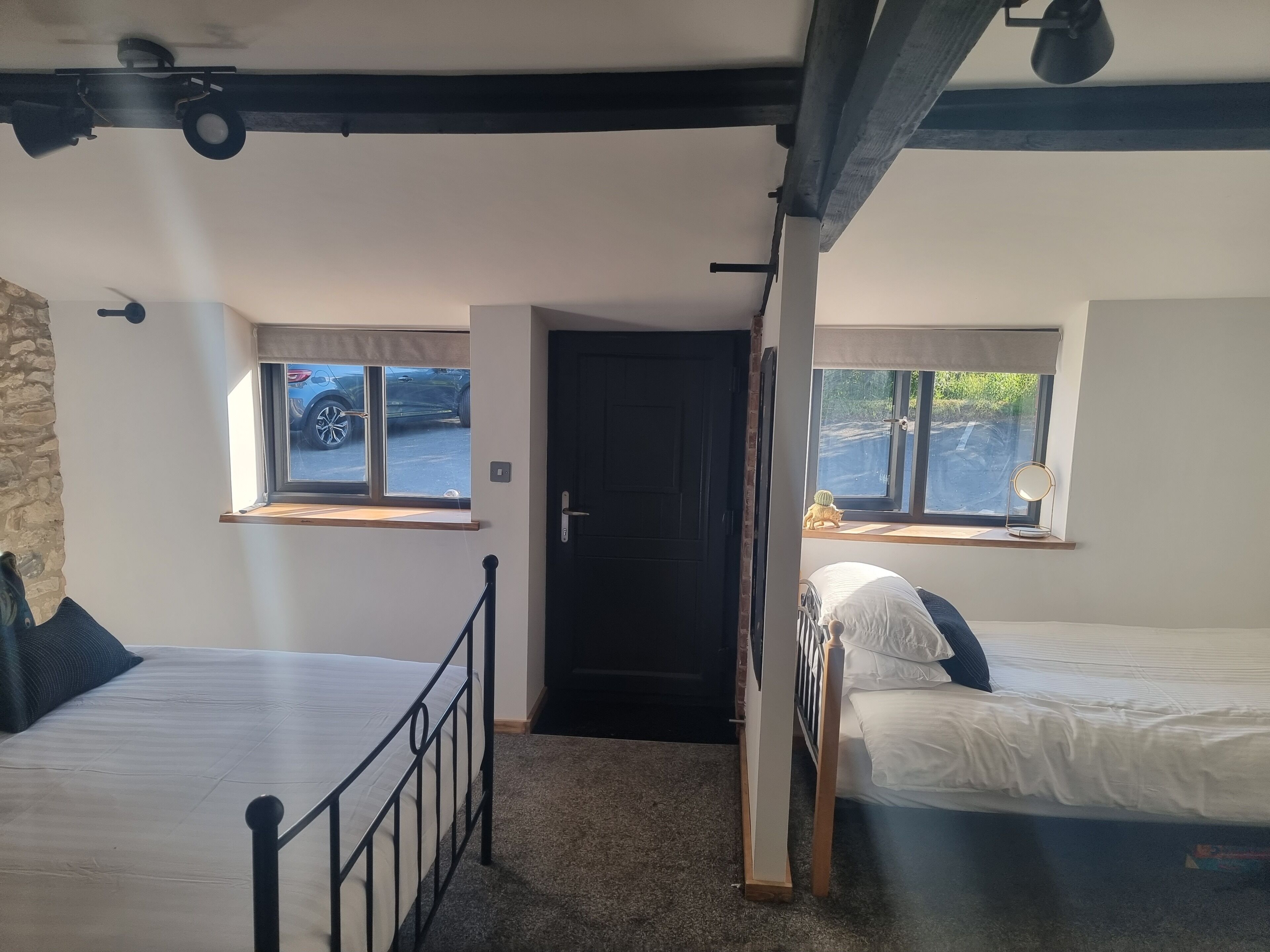 A room with two beds, a door, and windows with views of cars outside.
