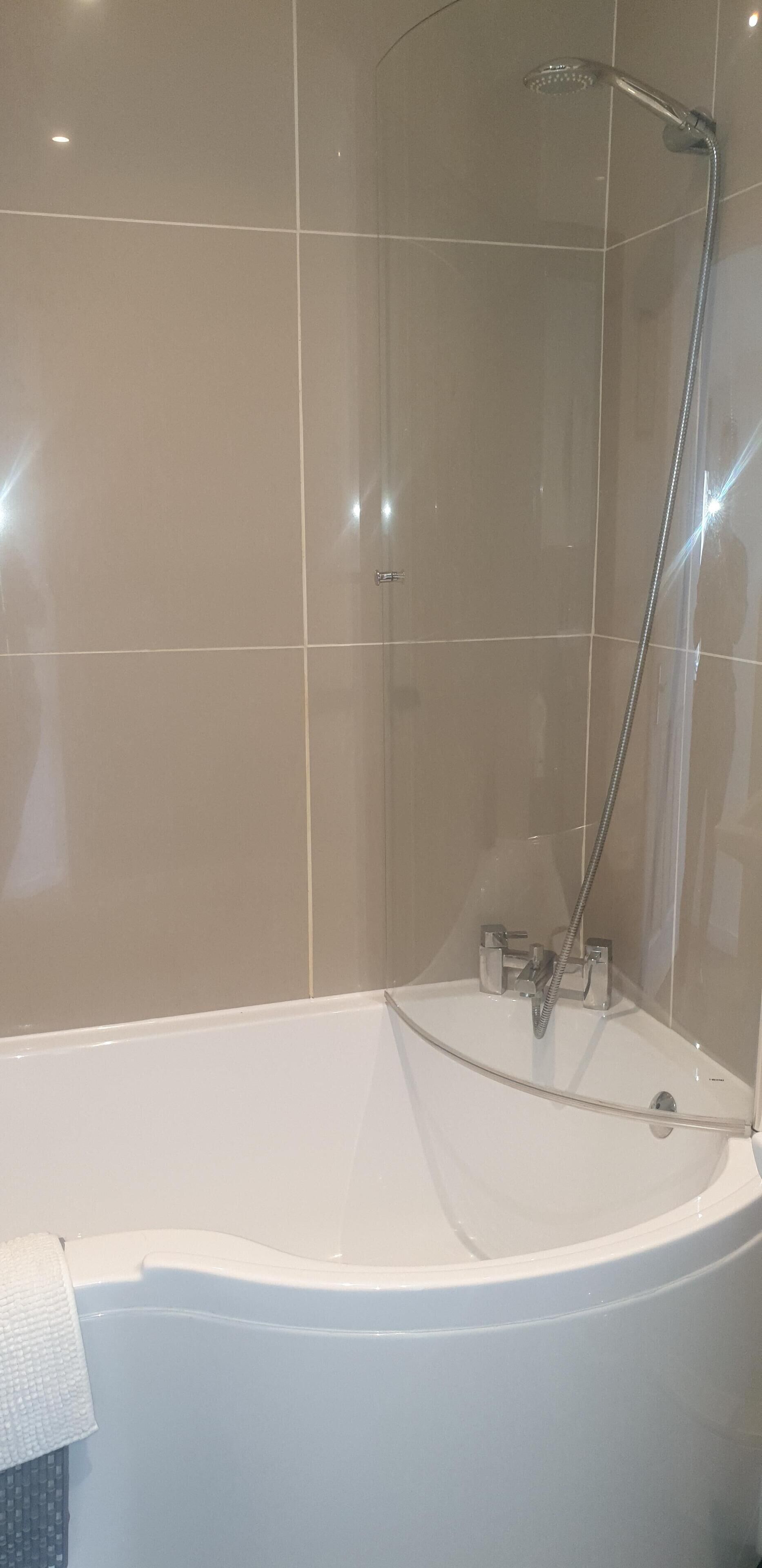 Une salle de bain moderne avec une baignoire sur pieds, une douchette et une cabine de douche en verre.
