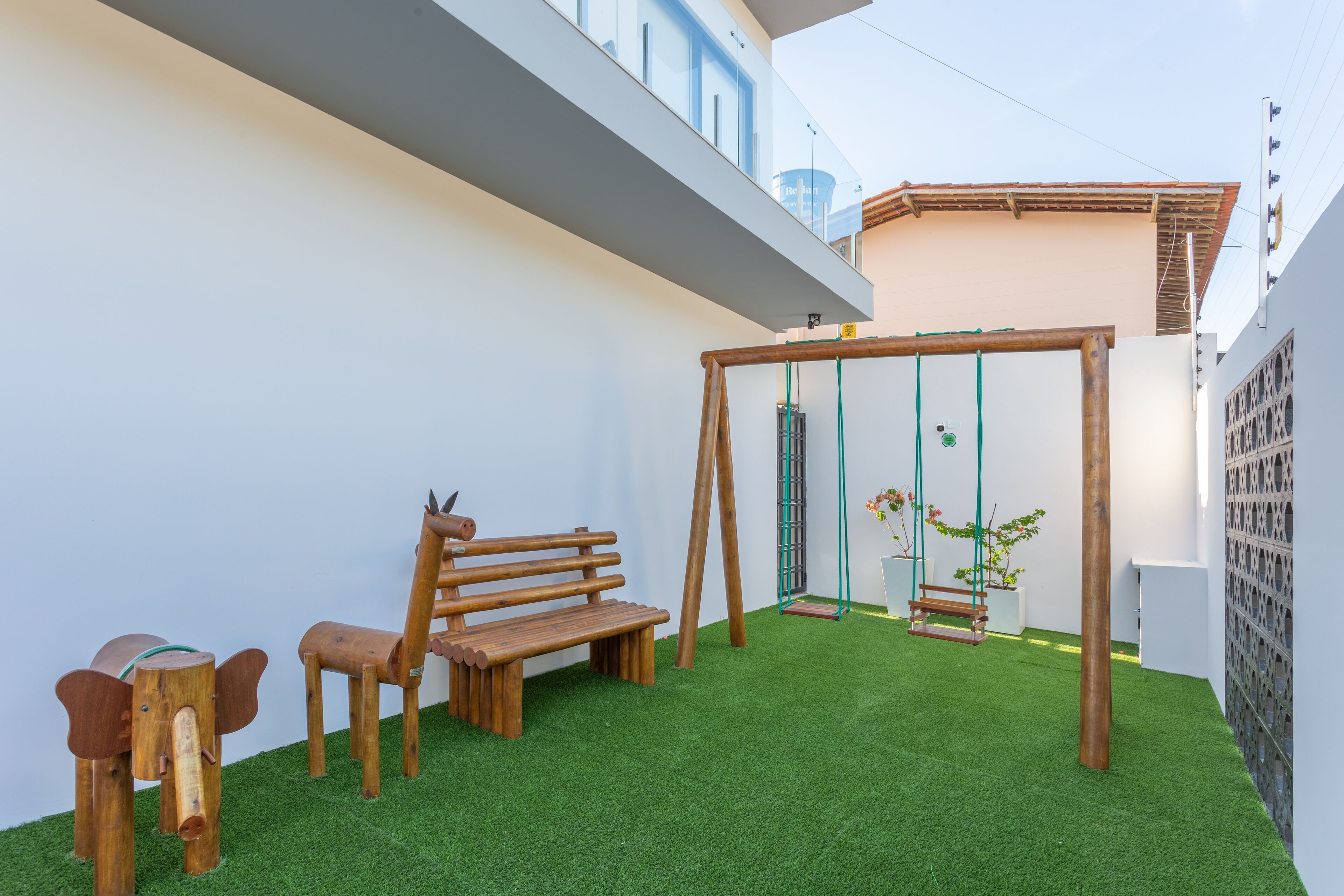 A patio with a wooden swing set, a bench, and a small table.