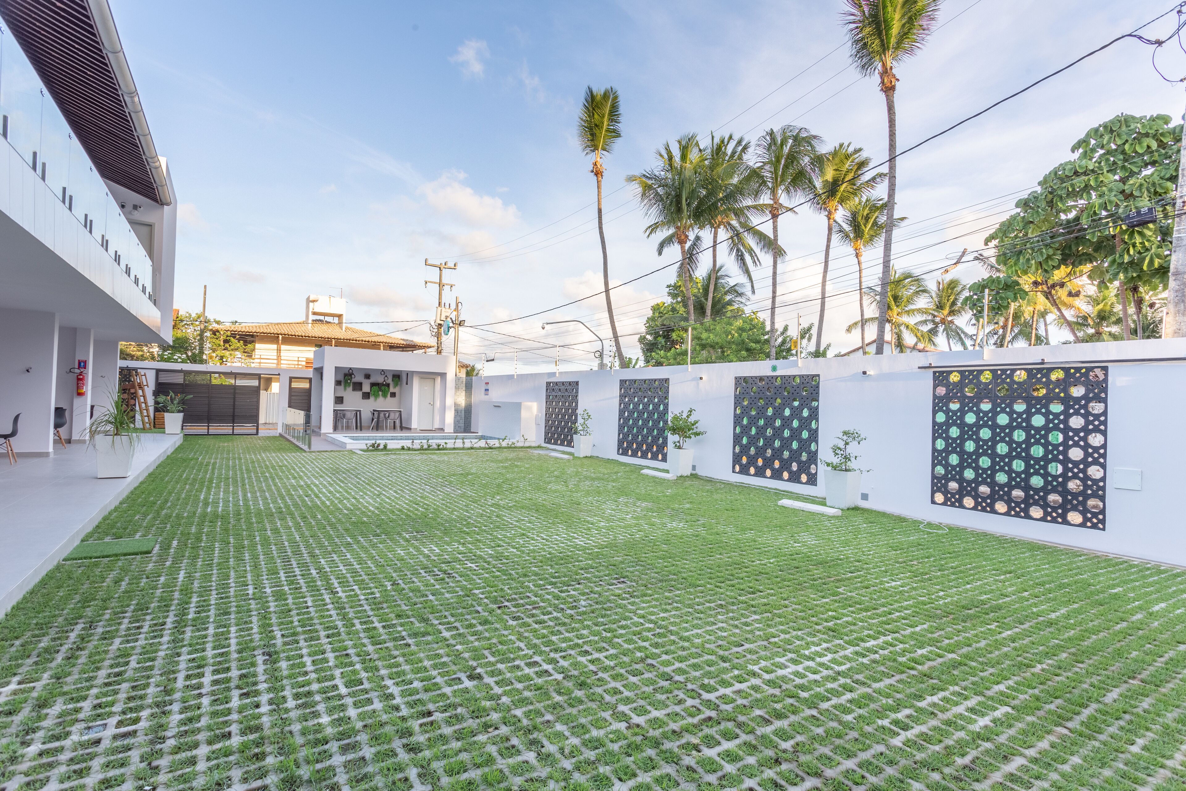 A modern building with a paved courtyard, palm trees, and a white exterior.