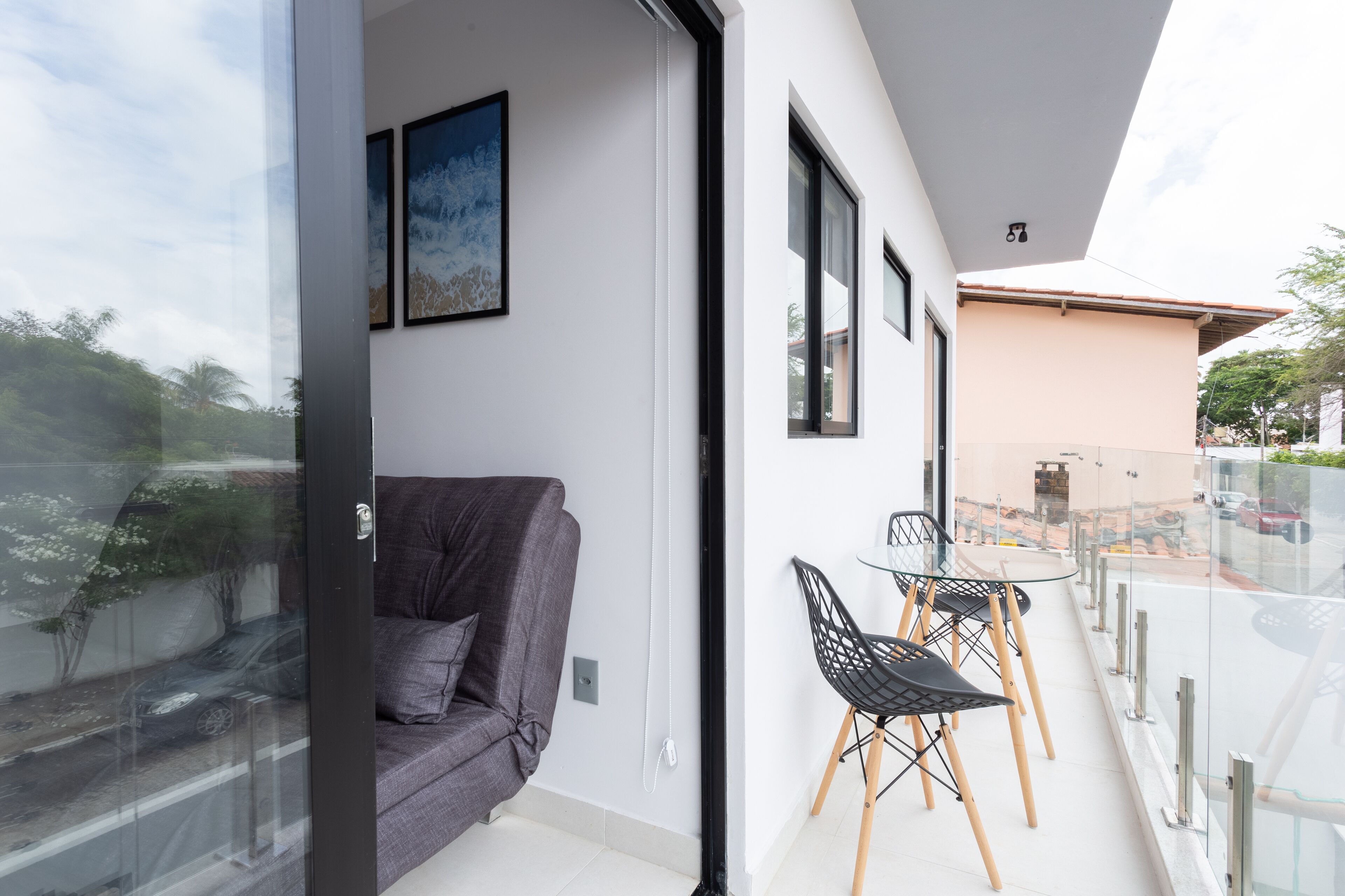 A modern living room with a gray sofa, a glass door leading to a balcony, and a small table with chairs.