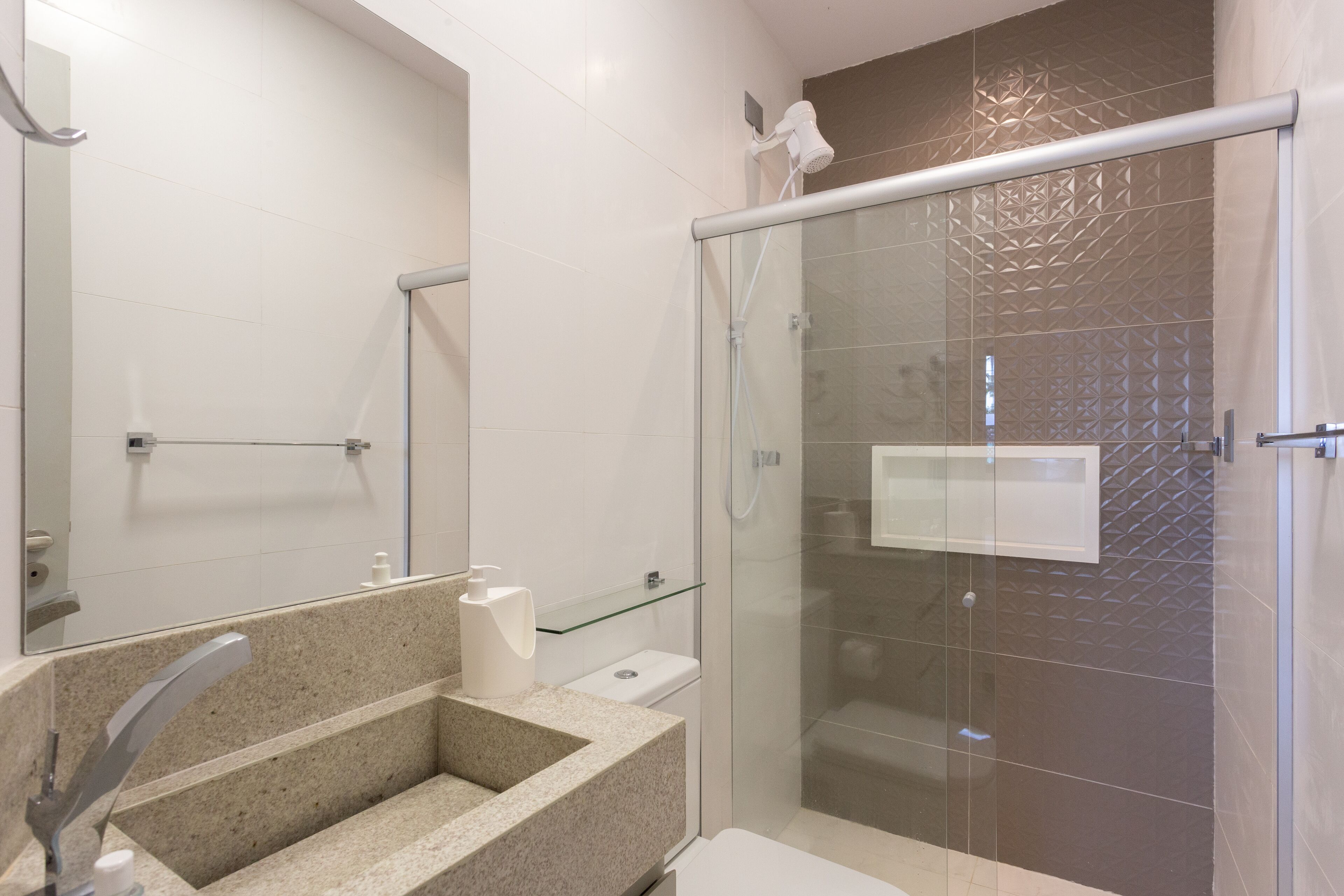 A modern bathroom with a glass shower enclosure, a granite sink, and a toilet.