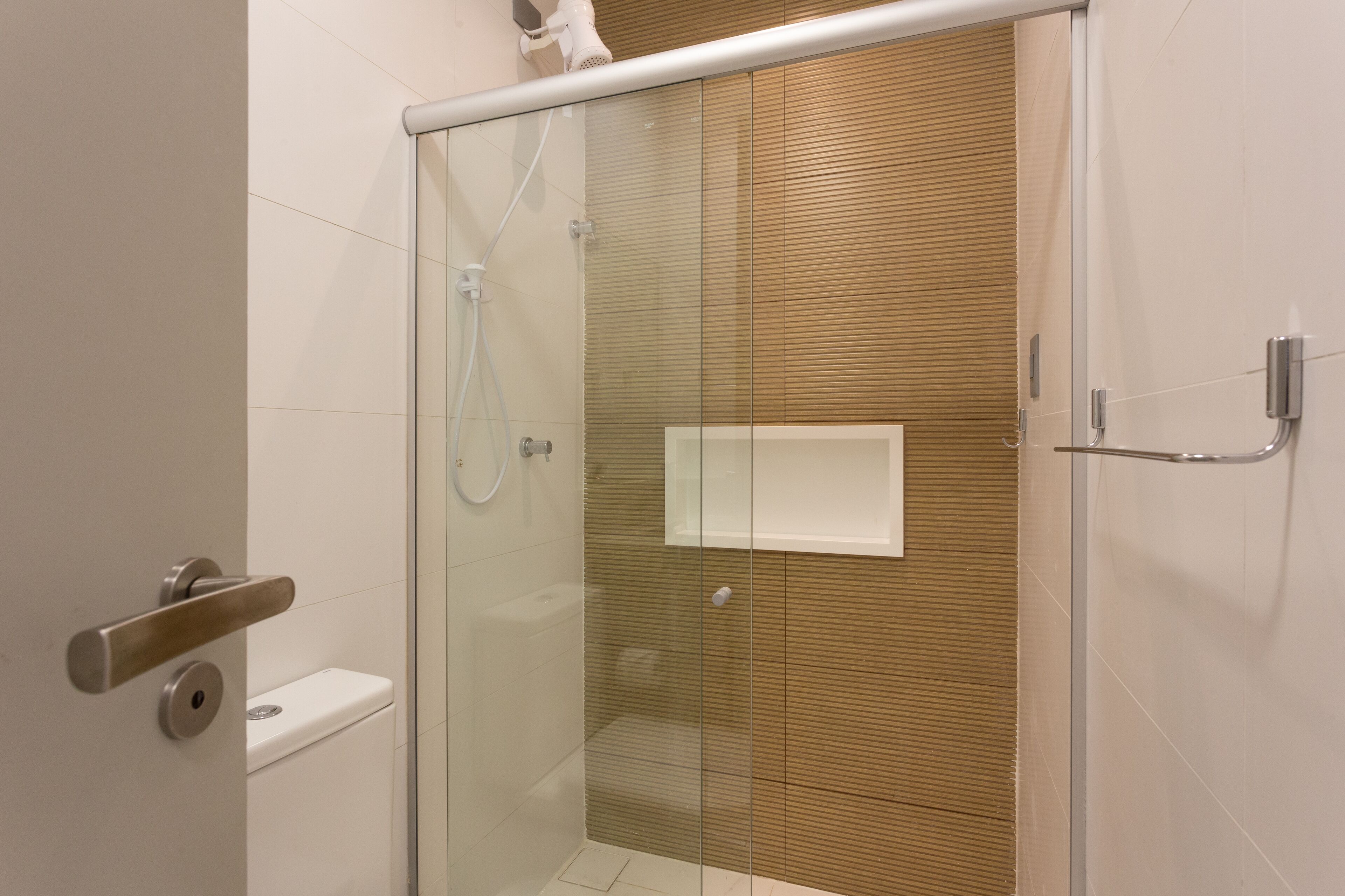 Een moderne badkamer met een douchecabine van glas, een toilet en een handdoekhouder.