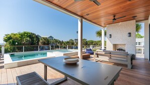 Une terrasse extérieure moderne avec une piscine, des meubles en bois et un mur en pierre.