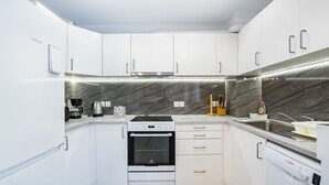 A modern kitchen with white cabinets, a Bosch dishwasher, a built-in oven, and a stainless steel sink. - Beautiful flat in superb location (Glyfada)