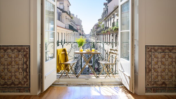 Un balcon ouvert avec une table et des chaises, une plante en pot et un vélo.